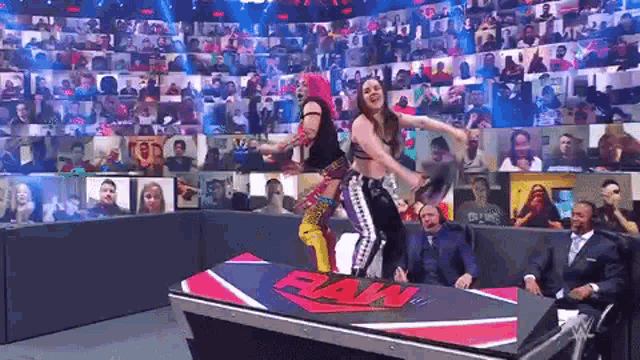 a couple of women are standing on top of a table in a wrestling ring .