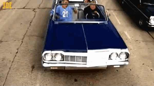a man in a blue shirt with the number 20 is driving a car