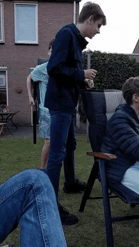 a group of young men are standing and sitting in a yard .