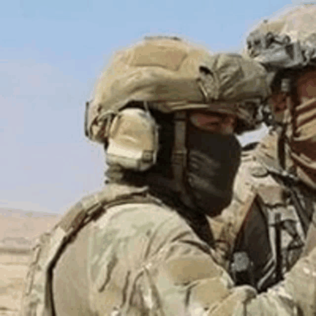 a soldier wearing a mask and a helmet is talking to another soldier .