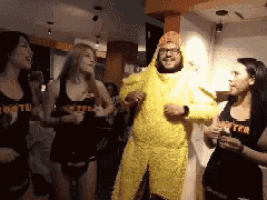 a man in a chicken costume is dancing with hooters girls
