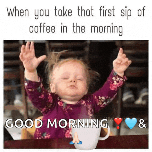 a baby girl is sitting at a table with her arms in the air and a cup of coffee .