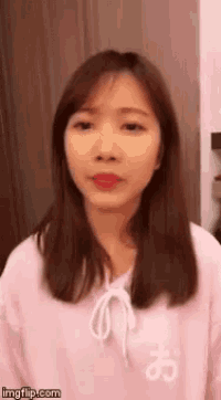 a woman is wearing a pink sweater with a white letter o on the front .