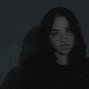 a blurry picture of a woman with long black hair behind a glass wall .