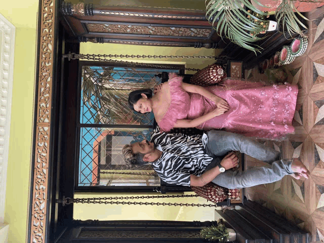 a woman in a pink dress and a man in a zebra print shirt are posing for a picture