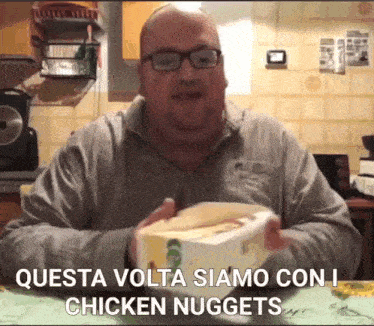 a man with glasses holds a box of chicken nuggets