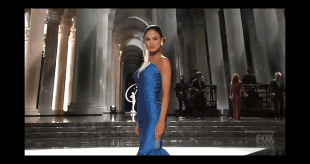 a woman in a blue dress is standing on a stage with a fox logo in the background