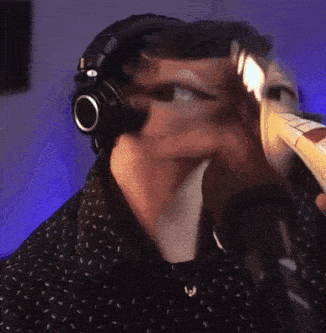 a man wearing headphones and a black shirt is drinking from a bottle