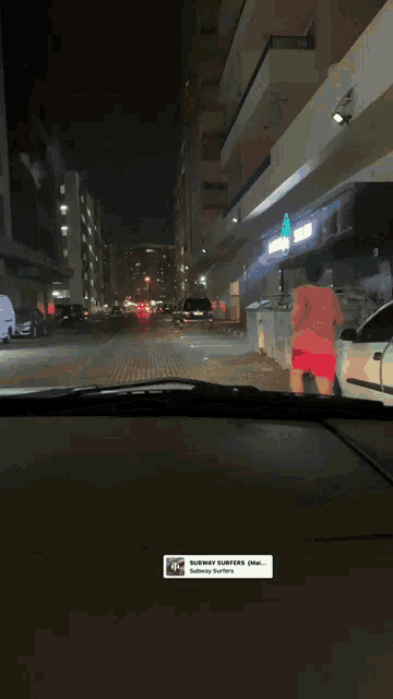 a man in a red shirt is running down a city street