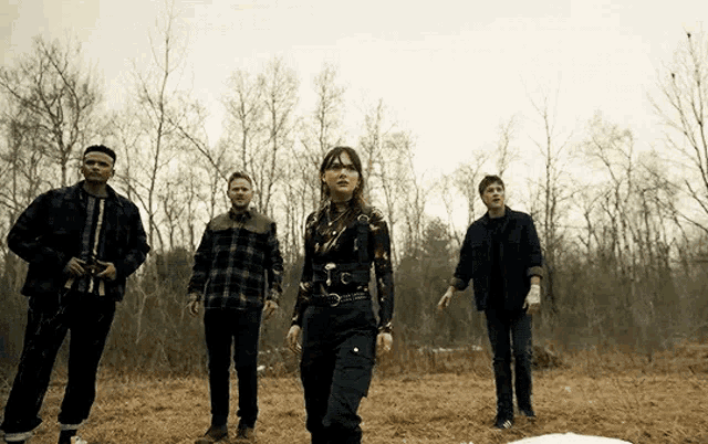 a group of people are standing in a field with trees behind them