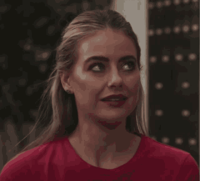a woman in a red shirt with earrings on her ears