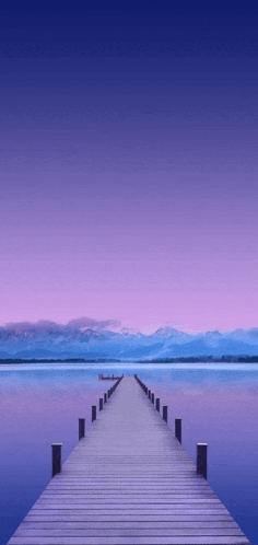 a dock with mountains in the background and a purple sky