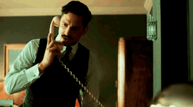 a man in a suit and tie is talking on a phone