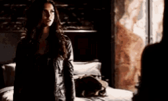 a woman in a leather jacket is standing next to a man in a dark room .
