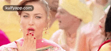 a woman is blowing a kiss with her hand in front of a crowd of people .