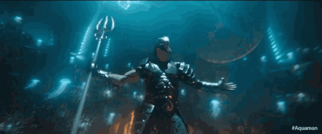 a man is holding a trident in the ocean with the words aquaman on the bottom