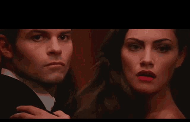 a man in a suit and a woman in a red dress are looking at each other .