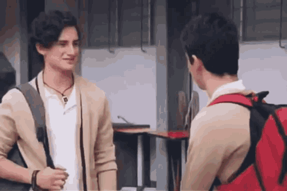 two young men are standing next to each other and talking to each other .