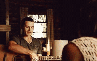 a man is playing an acoustic guitar in front of a woman