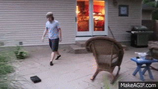 a man is walking on a patio next to a wicker chair .