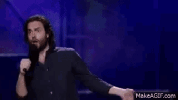 a man is singing into a microphone while dancing on stage .