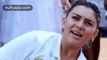a woman in a white shirt is making a funny face while sitting on the floor .
