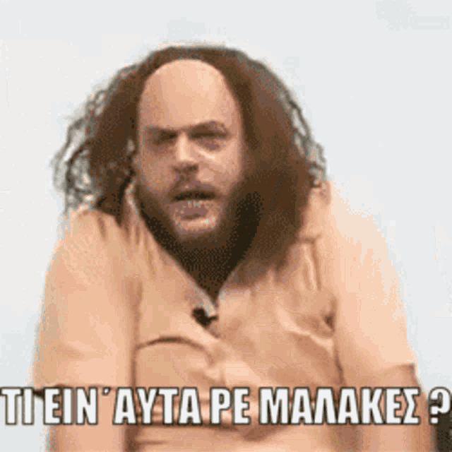 a man with long hair and a beard is wearing a tan shirt and has a caption in a foreign language