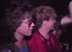 a man with curly hair wearing a cowboy hat is surrounded by two other men