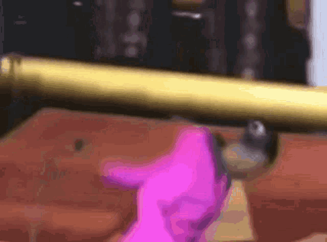 a person in a pink sweater is standing next to a gold pole .
