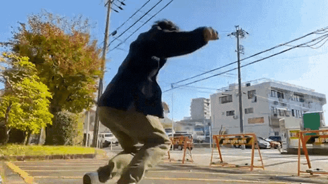 a man in a black jacket is jumping in the air in front of an orange barrier