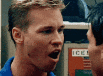 a man in a blue shirt is talking to another man in front of a locker with the word ice on it