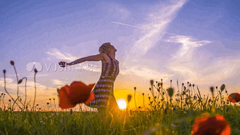 a woman is standing in a field with her arms outstretched at sunset