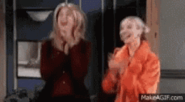 two women standing next to each other laughing and clapping .