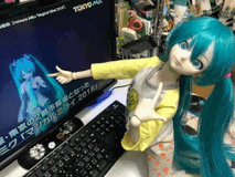 a doll with blue hair is standing in front of a computer monitor that says tokyo max