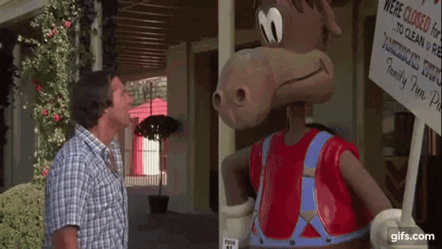 a man is standing next to a statue of a horse holding a sign that says family fun park .