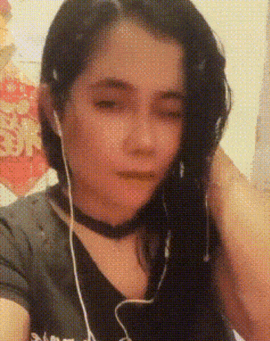 a girl wearing headphones and a choker looks at the camera with her eyes closed