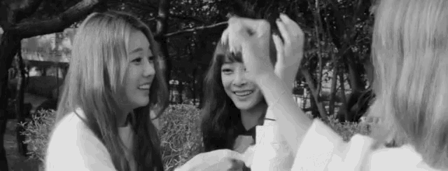 a black and white photo of three young women taking a picture of themselves .