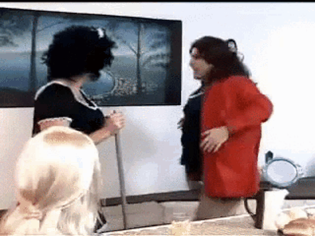a woman in a red coat is standing next to a woman in a black dress holding a broom .