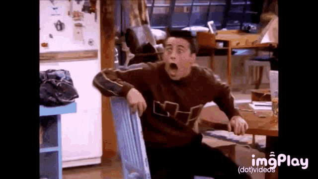 a man in a brown sweater is sitting in a chair with his mouth open