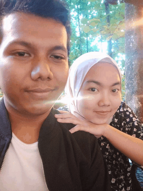 a man and a woman pose for a picture with the woman wearing a hijab