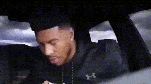 a man wearing a black under armour shirt is sitting in the back seat of a car