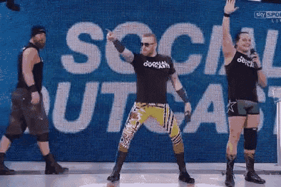 a group of wrestlers are standing in front of a sign that says social outcast
