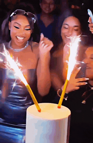 a group of women are celebrating a birthday with a cake and sparklers
