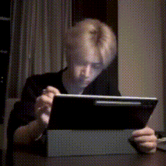 a man is sitting at a table using a tablet computer