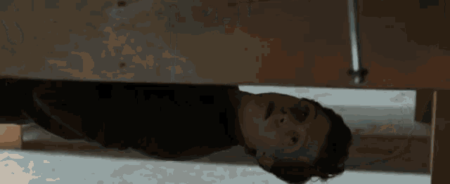 a young man is hanging upside down from a wooden beam .
