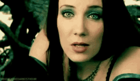 a close up of a woman 's face with blue eyes and a necklace .