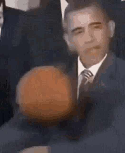 a man in a suit and tie is holding a pumpkin in his hand .