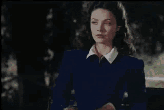 a woman in a blue jacket with a white collar is looking at something
