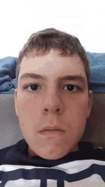 a young man in a striped shirt with the letter t on it looks at the camera
