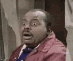 a man wearing a red jacket and tie is making a surprised face .